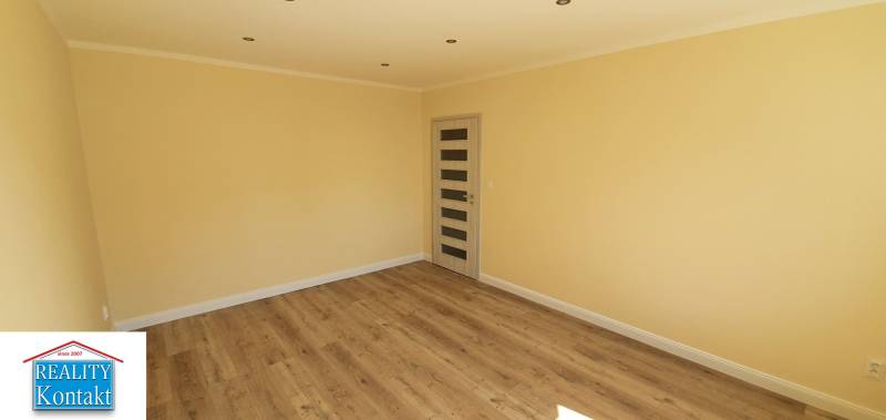 A bright room with a wooden decor floor and a door in a two-room apartment.