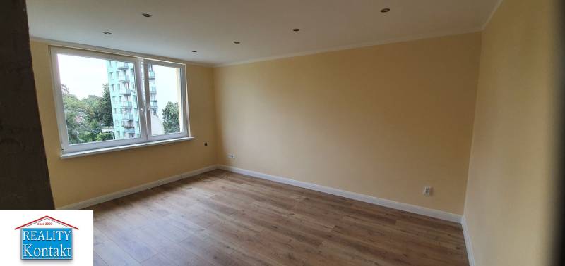 A room with yellow walls and a wooden decor floor in a two-room apartment.