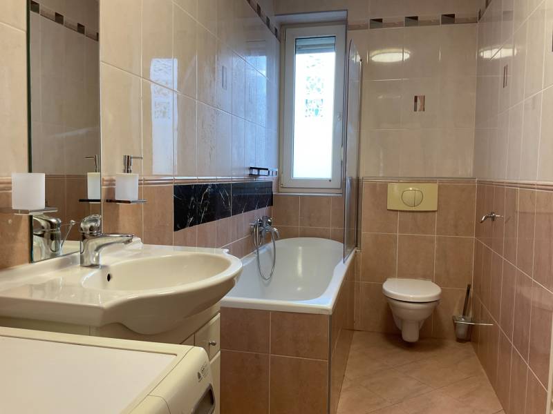 Bathroom with a bathtub, sink, toilet, and washing machine in a 3-room apartment.