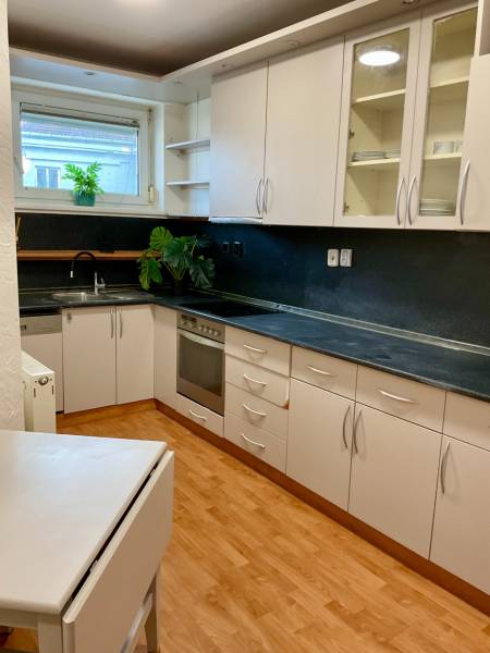 A kitchen in a 3-room apartment with white cabinets and a wood-patterned floor.