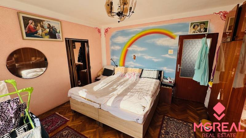 Bedroom in a family house with a rainbow painting on the wall and a wooden decor floor.