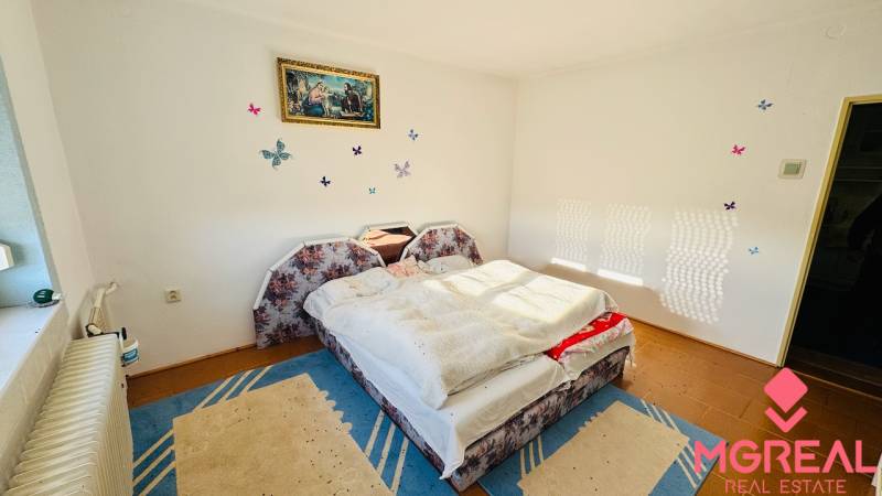 A bedroom in a family house with a wood-patterned floor and an upholstered bed.