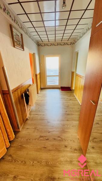 A hallway in a family house with a wooden decor floor and a decorated ceiling.
