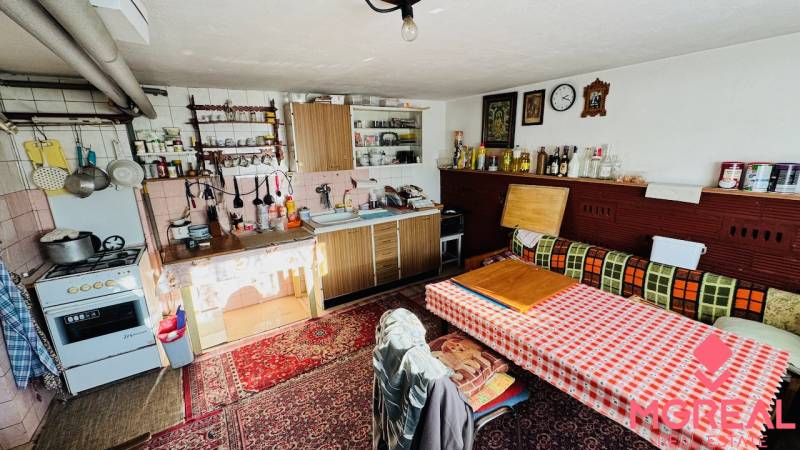 A kitchen in a family house with a carpet, wooden cabinets, and a dining table.