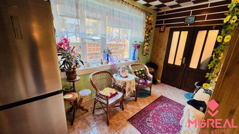 A family house with wicker furniture, a carpet, and lots of flowers in the interior.