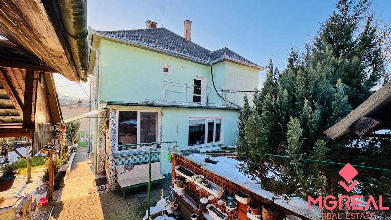 A family house in Horná Ves with a garden and a terrace, surrounded by greenery and decorative flower pots.