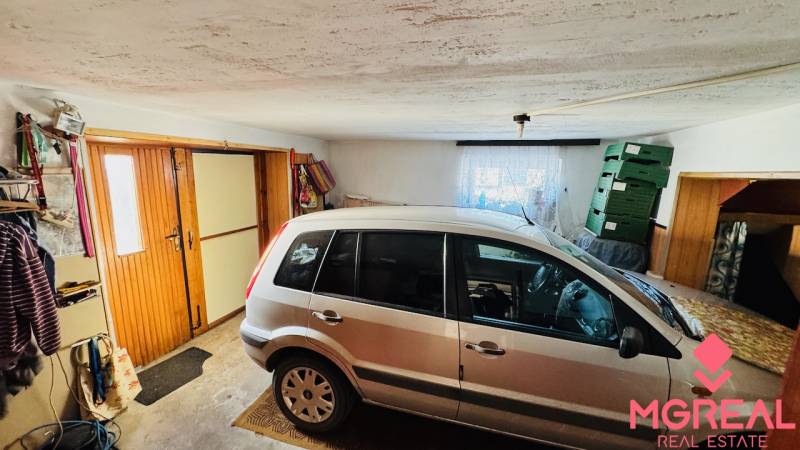 A garage in a family house with a car, boxes, and wooden doors.