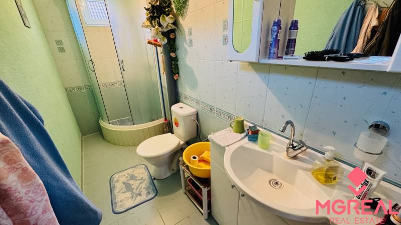 Bathroom in a family house with a toilet, shower, and sink with containers.