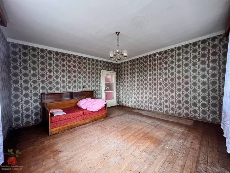 A room in a family house with retro wallpaper and a wooden decor floor.