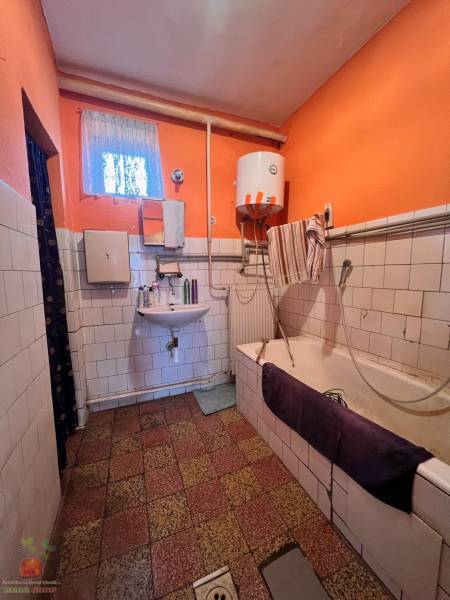 A bathroom in a family house with orange walls and older furnishings.