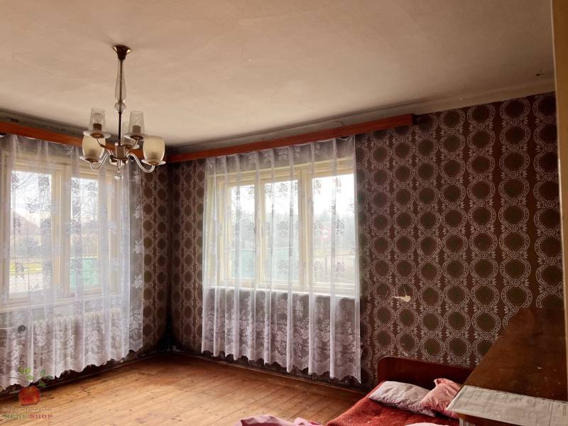 A room in a family house with wallpaper, a chandelier, and a wooden decor floor.