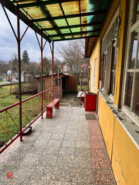 Terrace with paving of a family house in Komjatice, with a garden view and a bench.