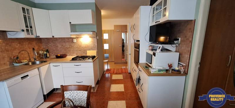 A kitchen in a 3-room apartment with white cabinets and a gas stove.