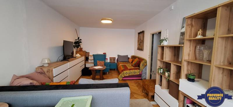 A living room in a 3-room apartment with a wooden decor floor, colorful sofas, and furniture.