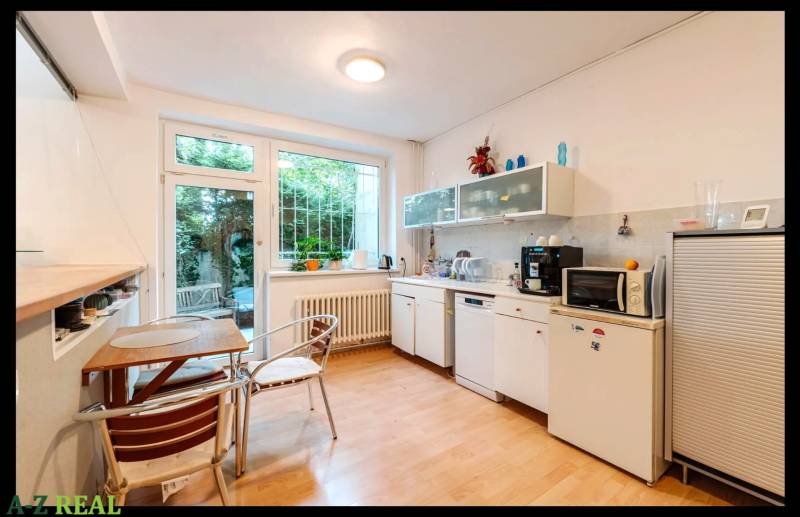 A kitchen in a family house with a wooden decor floor and a view of the garden.