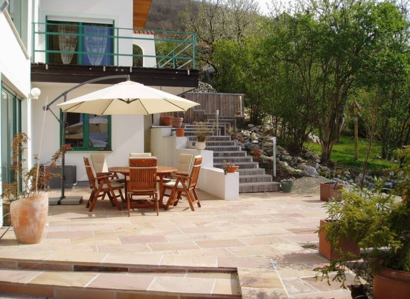 The terrace of a family house in Hainburg an der Donau with wooden furniture and a sunshade.