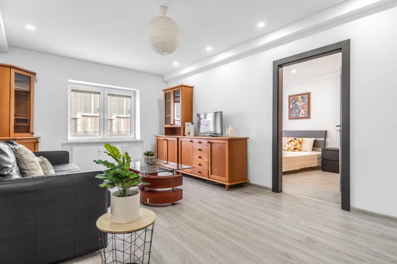 Living room with a dark sofa, wooden furniture, television, and wood-patterned flooring.