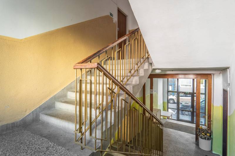 Staircase of a residential building with a window facing the street, entrance to a 3-room apartment.