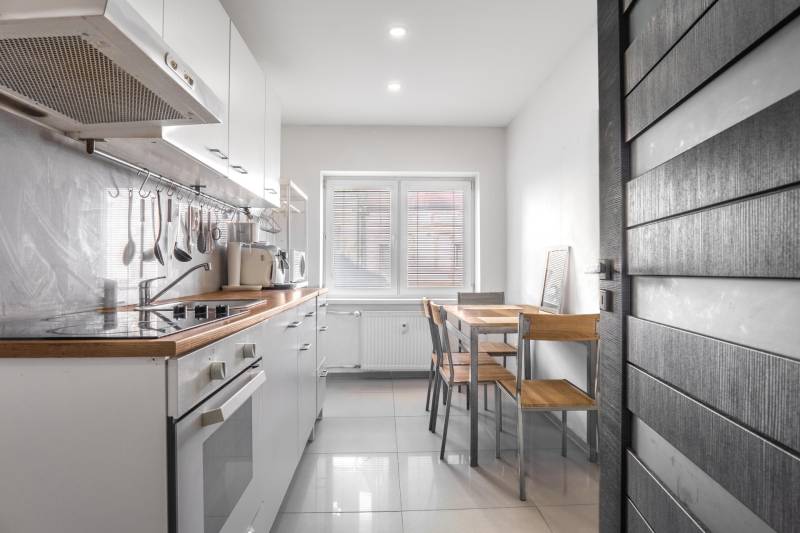 A kitchen in a 3-room apartment with white cabinets and a dining table by the window.