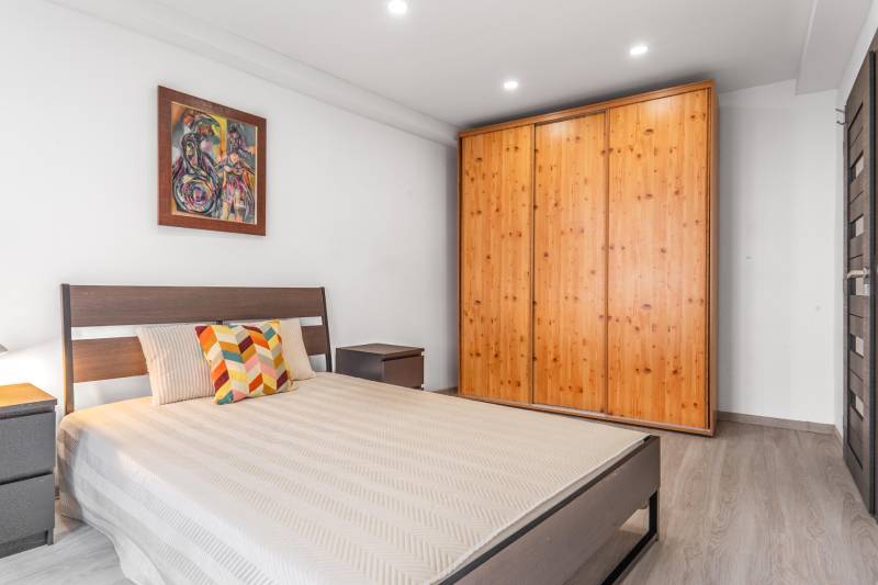Bedroom in a 3-room apartment with a bed, wooden wardrobe, and floor with wooden decor.
