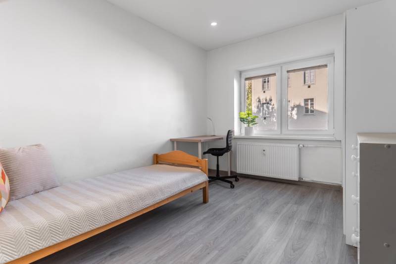 A room in a 3-room apartment with a bed, a table, and a floor with a wooden decor.