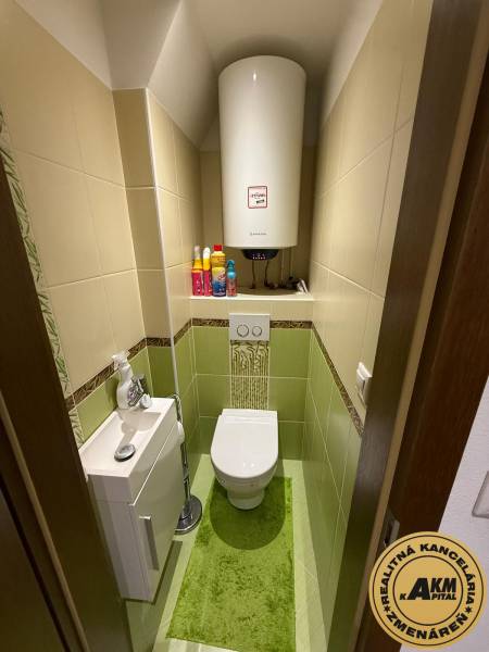 Bathroom in a 2-room apartment with a toilet and a sink, tiled with light tiles.