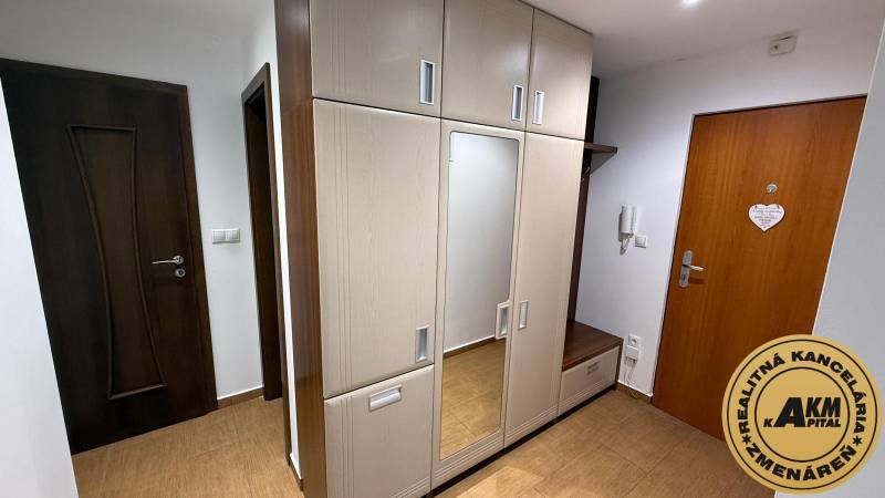 Hallway in a 2-room apartment with a built-in wardrobe, mirror, and floor with a wooden decor.