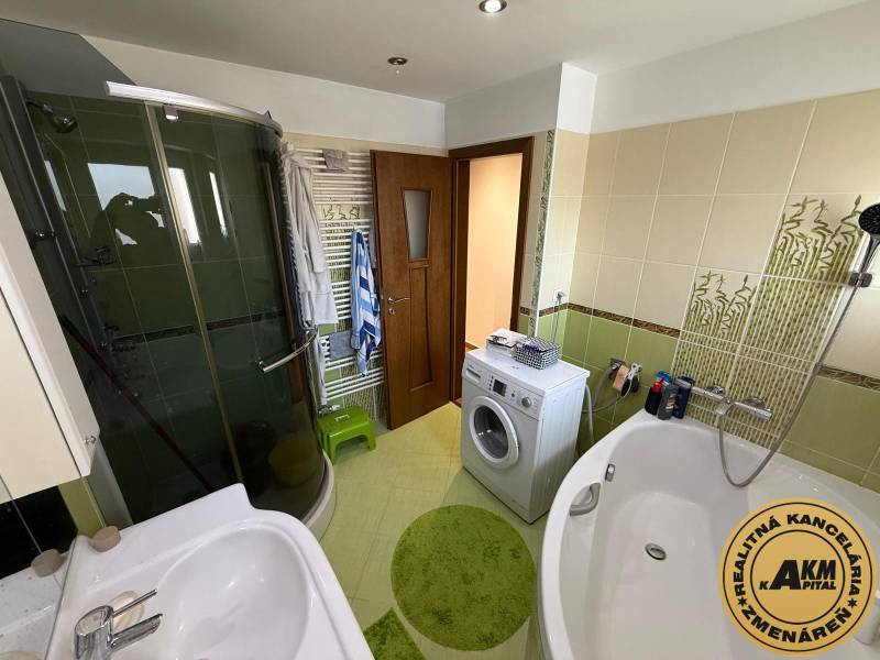 A bathroom in a 2-room apartment with a bathtub, shower, and washing machine, patterned tiles.