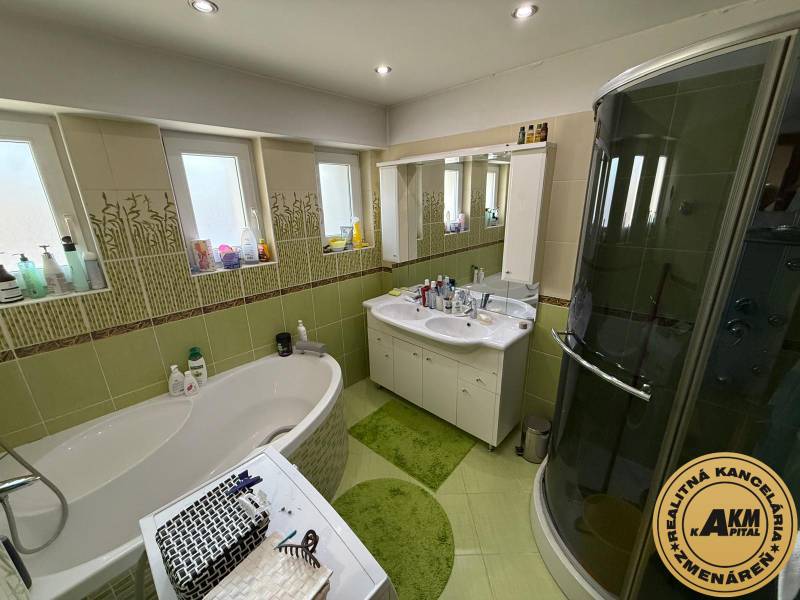 A bathroom in a 2-room apartment with a bathtub, shower, and green tiles.