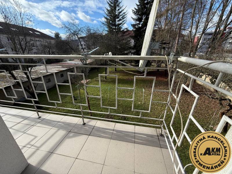 The balcony of a 2-room apartment on Ľ. Štúra in Zvolen with a view of the garden and trees.