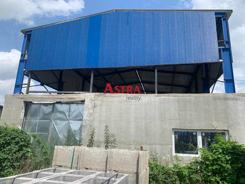 Warehouses and halls in Čaňa with a blue roof structure and concrete wall.