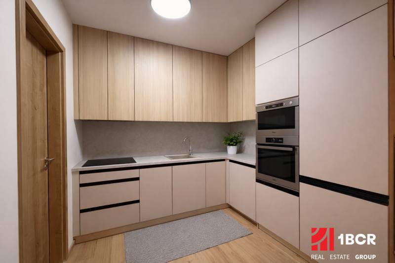 A kitchen in a studio apartment with a wood-patterned floor and modern appliances.