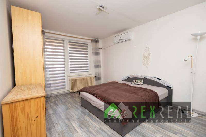 Bedroom in a 3-room apartment with wood-patterned flooring, a bed, and a cabinet.