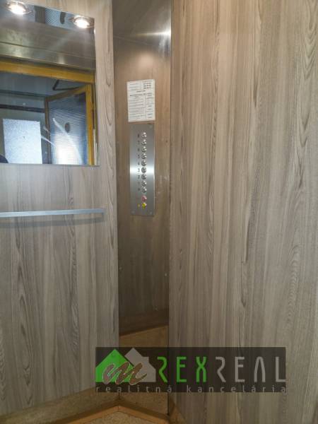 The interior of the elevator with wood decor panels and a mirror in a 3-room apartment.