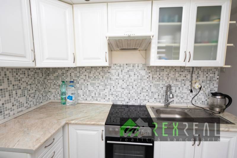 A kitchen in a 3-room apartment with white cabinets and mosaic tiles.