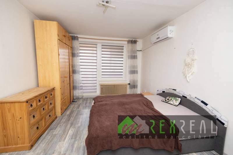 Bedroom in a 3-room apartment with wood-patterned flooring, a wardrobe, and a bed.