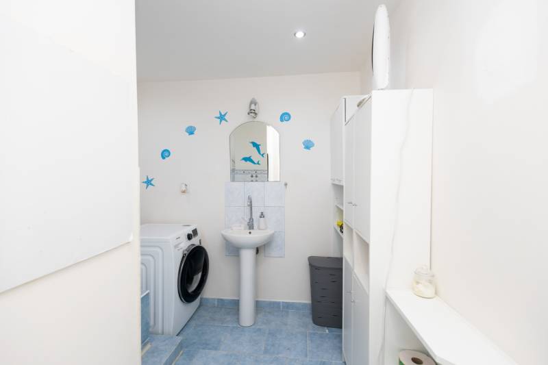 A bathroom with light cabinets, a sink, and a washing machine in a 3-room apartment.