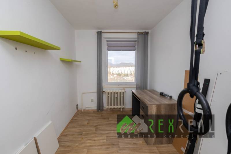 A room with a wooden decor floor in a 3-room apartment, with a view of the city.