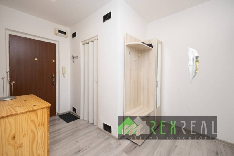 The entrance hall of a three-room apartment with a wooden decor floor and a built-in wardrobe.