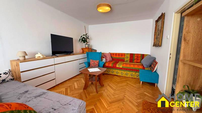 A living room in a 3-room apartment with a wooden decor floor and colorful sofas.