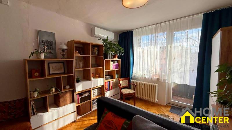 Living room in a 3-room apartment with a wooden decor floor, a bookshelf, and comfortable seating.