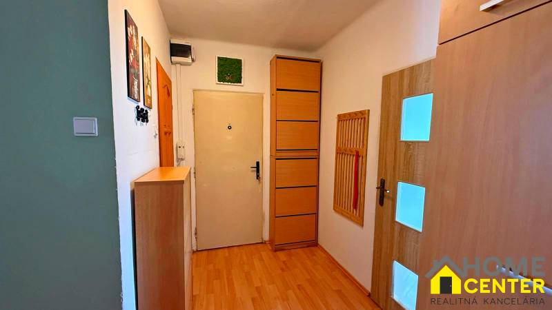 A hallway in a 3-room apartment with light furniture and a wooden decor floor.