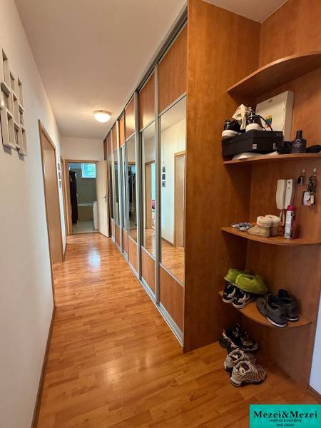 A hallway in a 2-room apartment with a wooden decor floor and a mirrored wardrobe.
