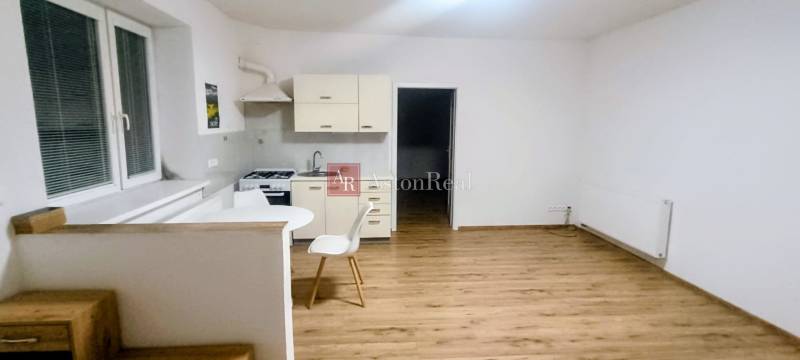 A kitchen in a family house with a wooden decor floor and simple furniture.