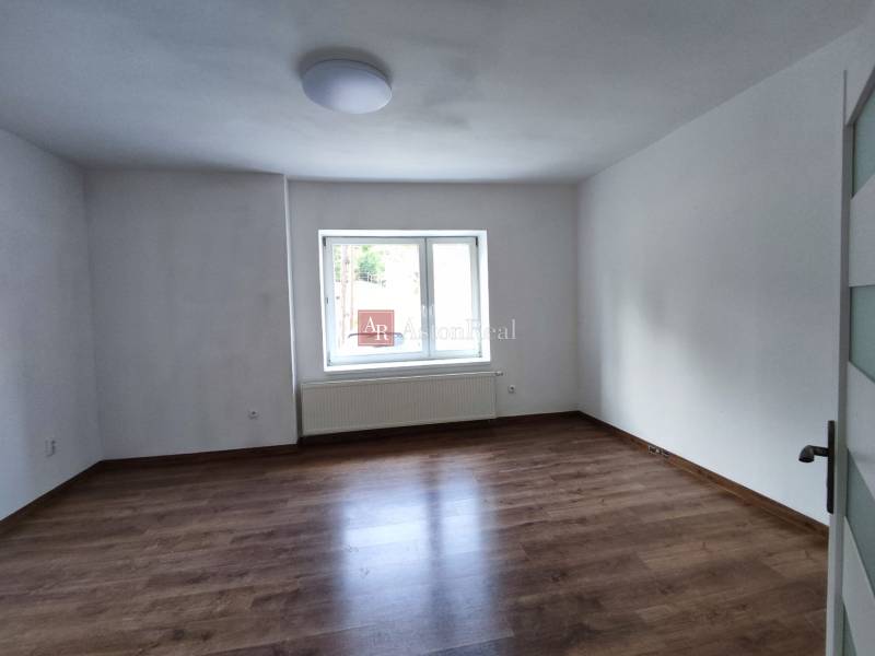 A room in a family house with neutrally painted walls and a wooden decor floor.