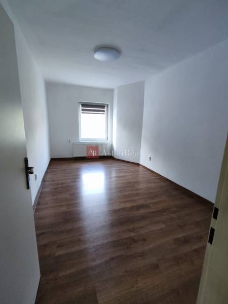 A spacious room in a family house with a wooden decor floor and white walls.
