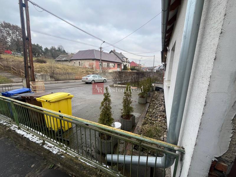 A family house on Osloboditeľov Street in Lieskovec, with garbage bins and a parked car.