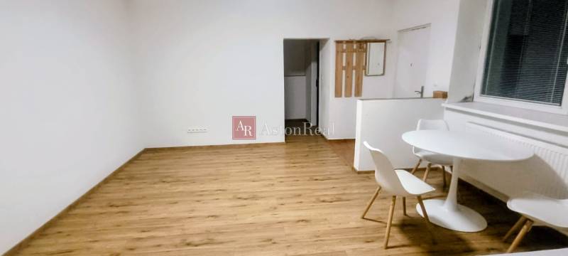 A room with a wooden decor floor, a white table, and chairs in a family house.