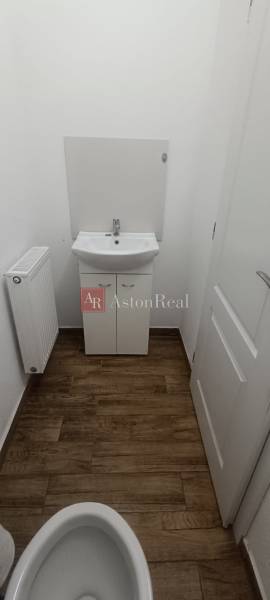 A bathroom in a family house with a sink, radiator, and a floor with a wooden decor.