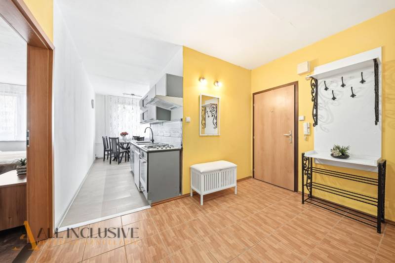 Entrance hall in a 3-room apartment with a wooden decor floor, leading to the kitchen and dining room.